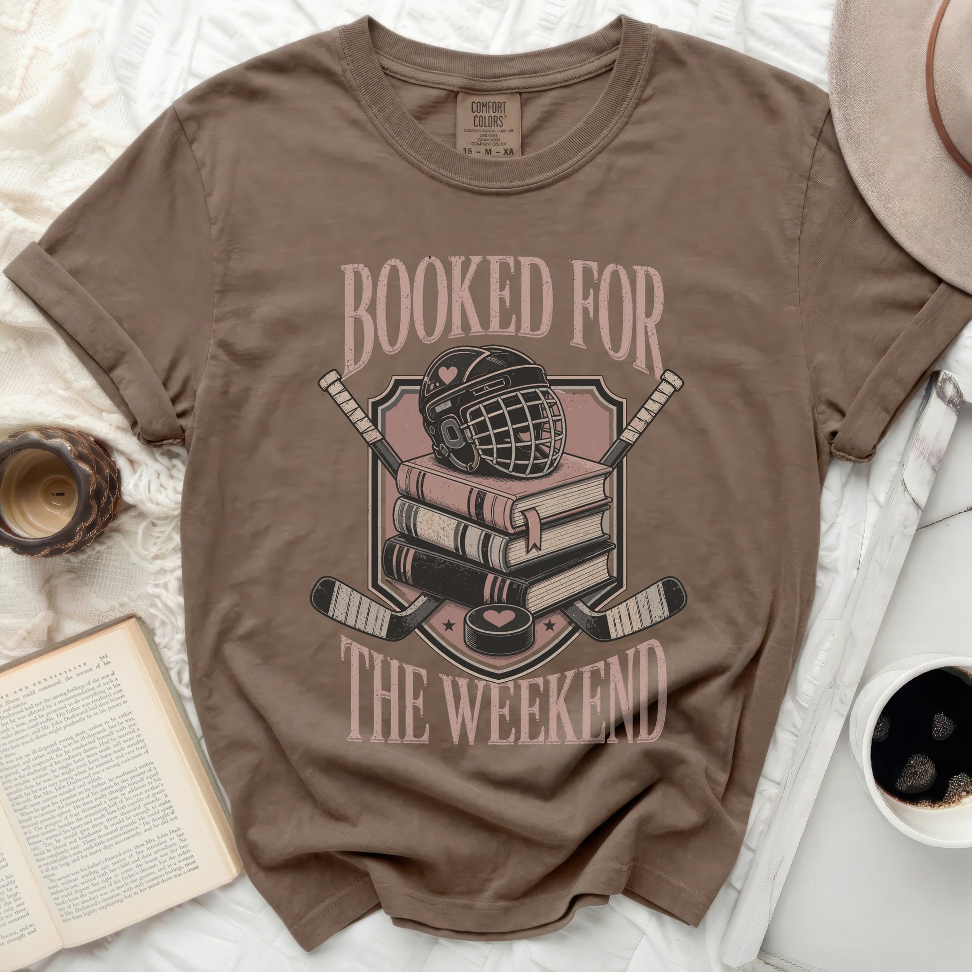 T-shirt with stacked books, hockey helmet, and crossed hockey sticks graphic.