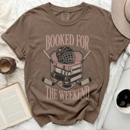 T-shirt with stacked books, hockey helmet, and crossed hockey sticks graphic.