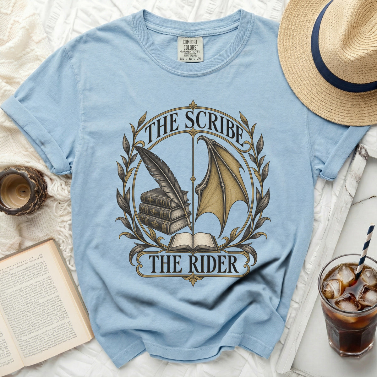 Light blue t-shirt with "The Scribe" and "The Rider" graphic featuring a feather, books, and a dragon wing.
