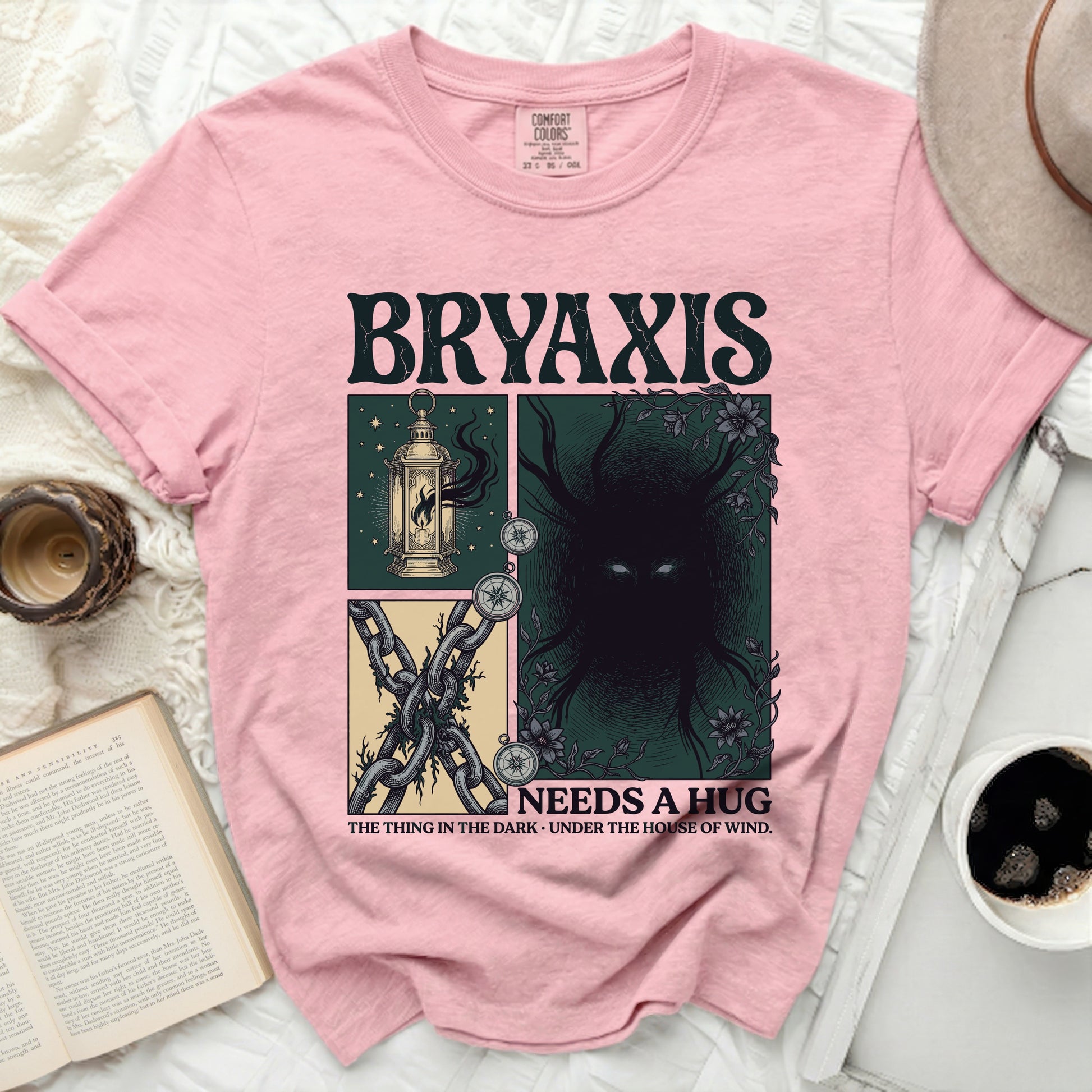 Pink Comfort Colors t-shirt with "BRYAXIS NEEDS A HUG" and dark graphic art.