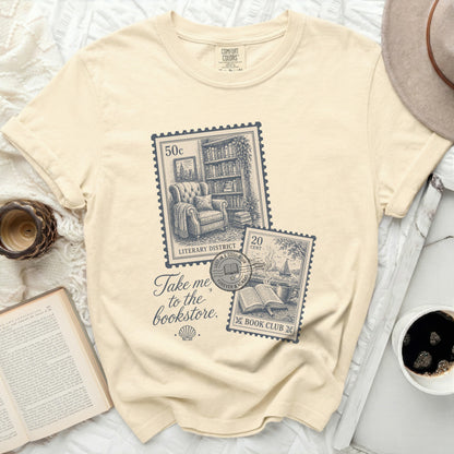 Cream t-shirt with "Take me to the bookstore" and vintage stamp graphic.