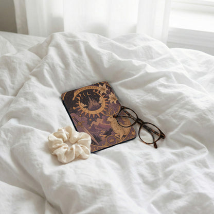 Journal with celestial art, glasses, and scrunchie on rumpled white sheets.