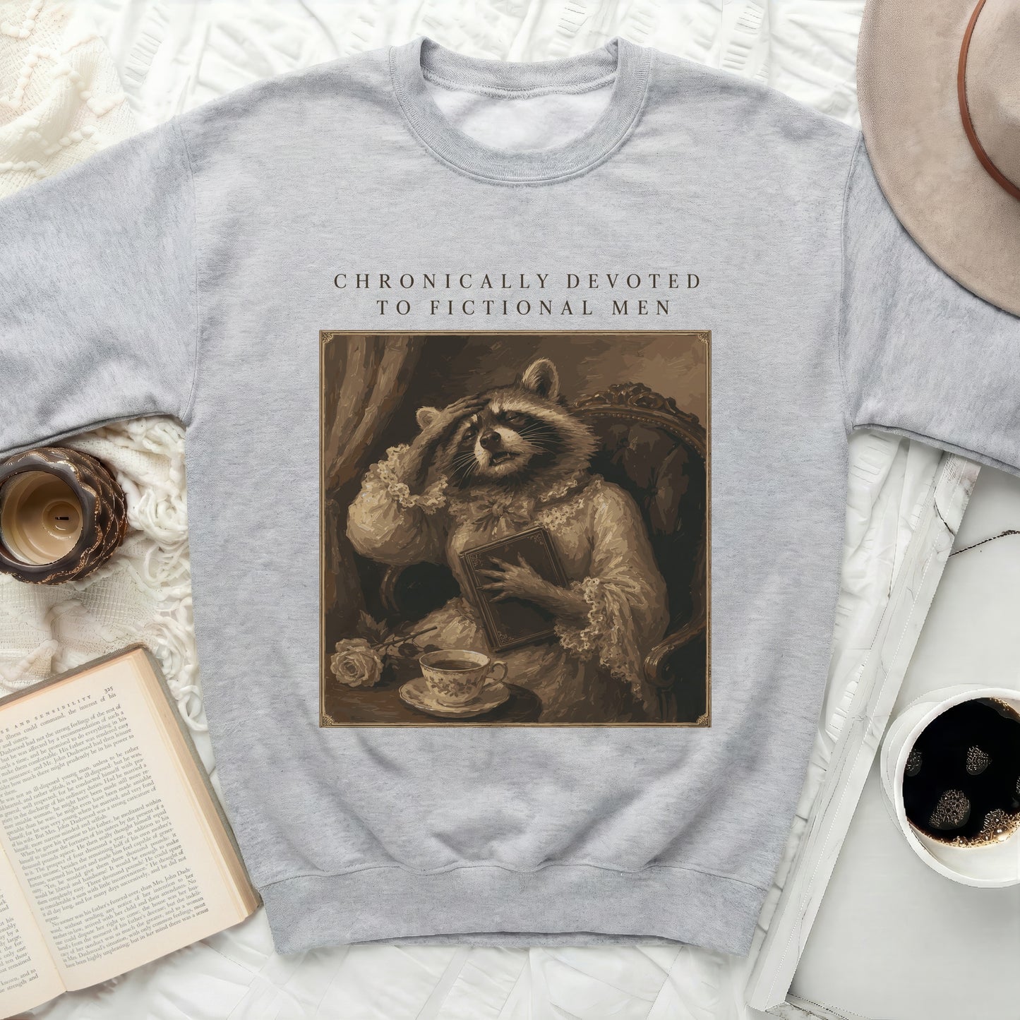 Grey sweatshirt with "CHRONICALLY DEVOTED TO FICTIONAL MEN" and raccoon graphic.