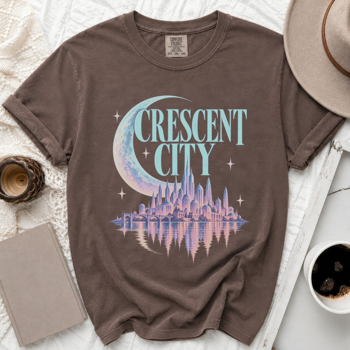 Brown t-shirt with "CRESCENT CITY" text, crescent moon, and city skyline graphic.