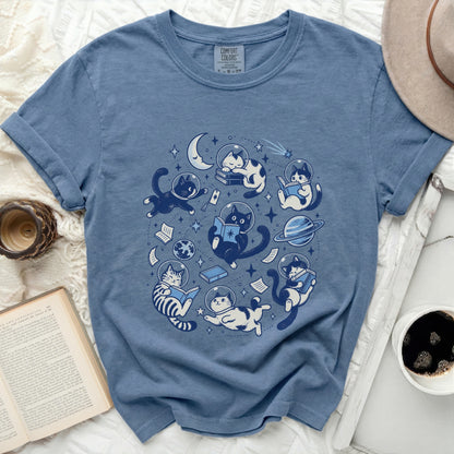 Blue t-shirt with space cats reading books around a crescent moon.