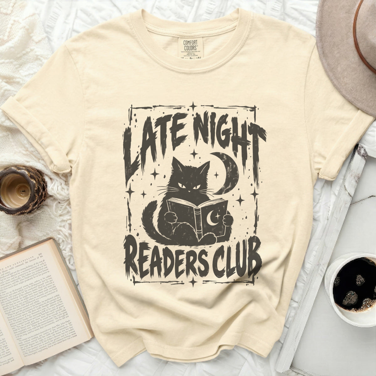Cream t-shirt with black graphic of a cat reading a book, moon, and text "LATE NIGHT READERS CLUB".
