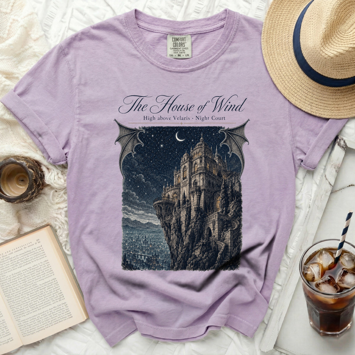 Lavender t-shirt with "The House of Wind" design of a castle on a cliff.