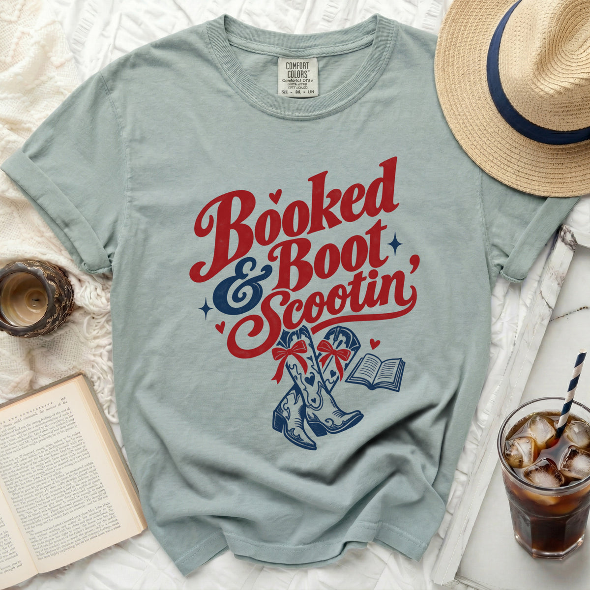 Light blue t-shirt with "Booked & Boot Scootin'" text, cowboy boots, and a book.