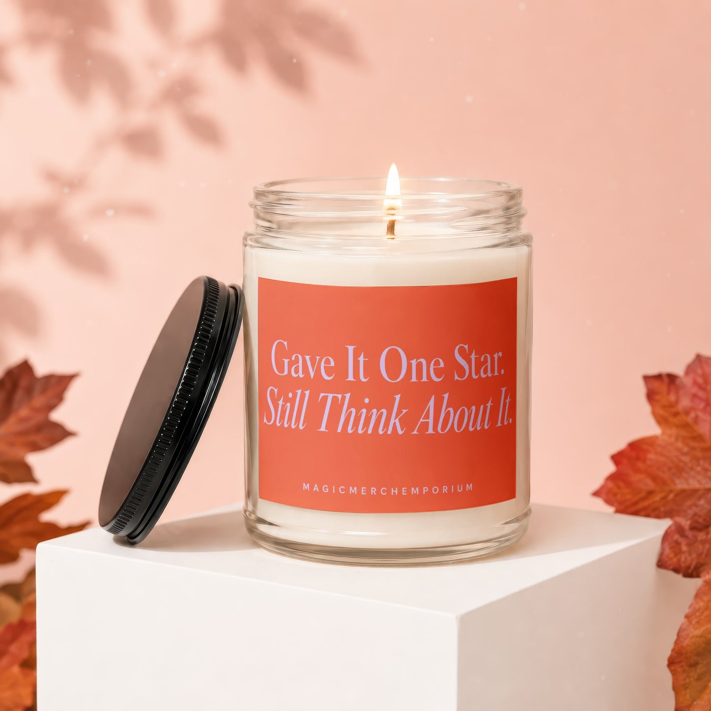 Glass candle with orange label reading "Gave It One Star. Still Think About It."