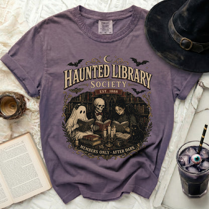 Purple t-shirt with "Haunted Library Society" graphic of ghost, skeleton, and witch.