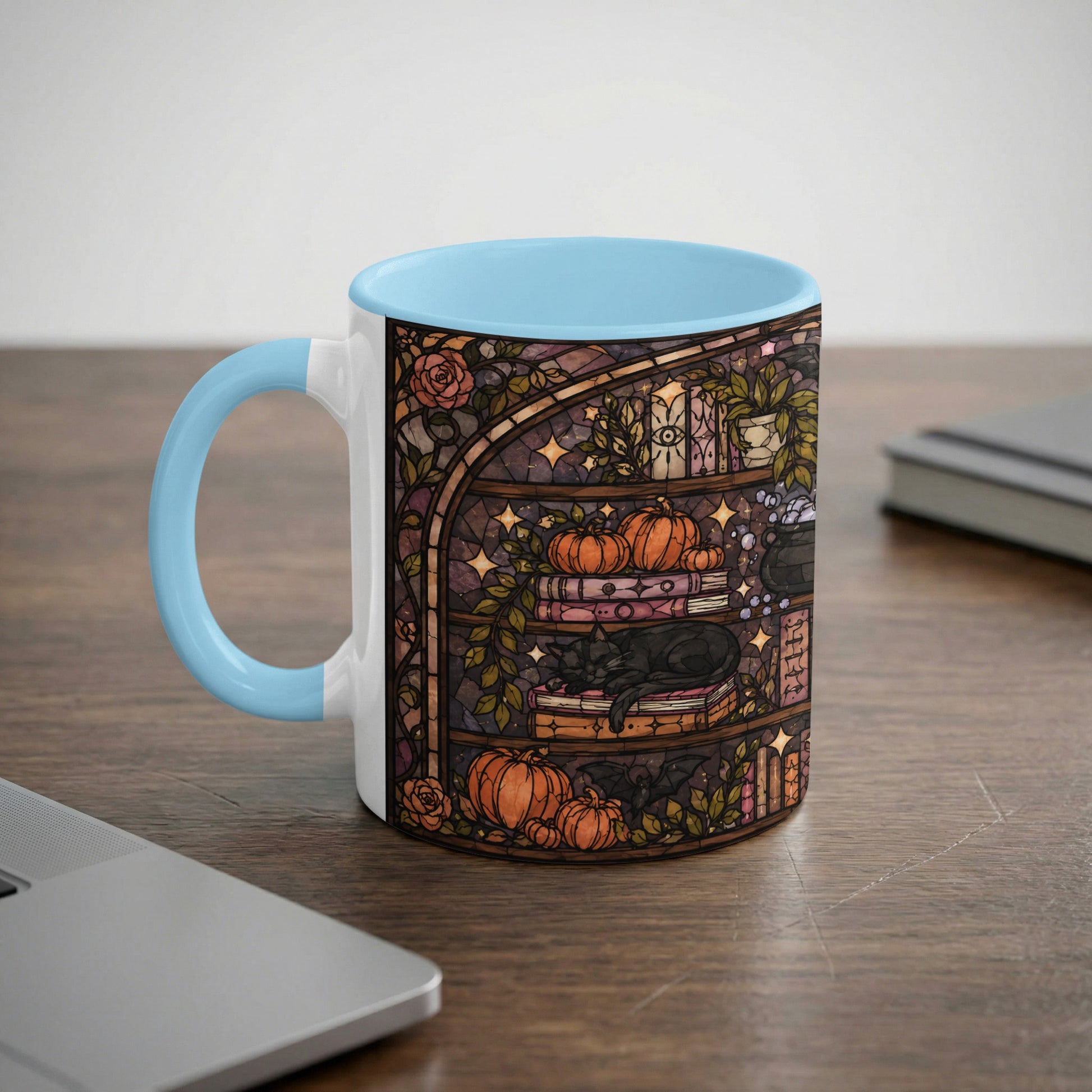 White mug with blue interior featuring a stained-glass design of a black cat on books with pumpkins.