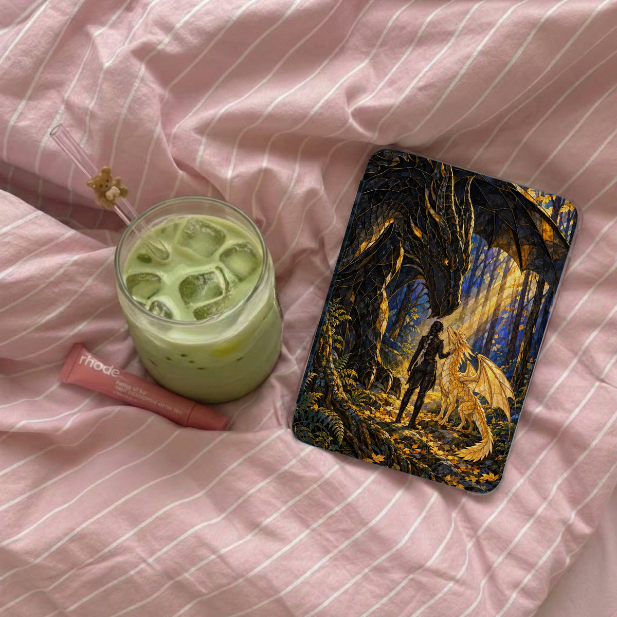Phone case featuring dragons and a woman in a forest, next to a matcha drink.