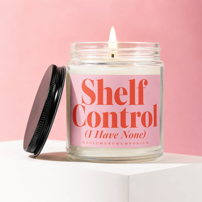 Jar candle with lit wick and pink label reading "Shelf Control (I Have None)".