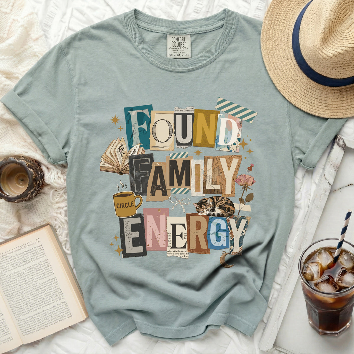 Green t-shirt with "Found Family Energy" text collage and sleeping cat graphic.