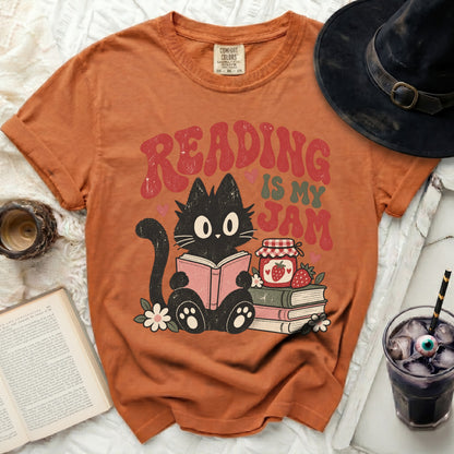 Orange t-shirt with black cat reading a book, text "READING IS MY JAM".