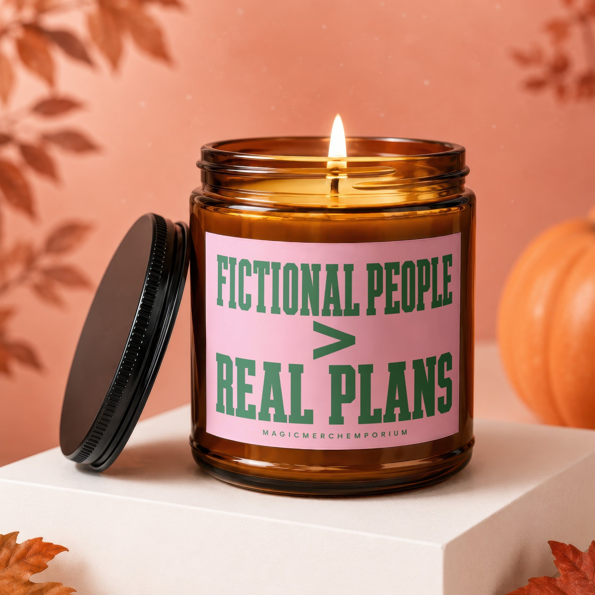 A lit amber glass candle with "FICTIONAL PEOPLE > REAL PLANS" on a pink label.