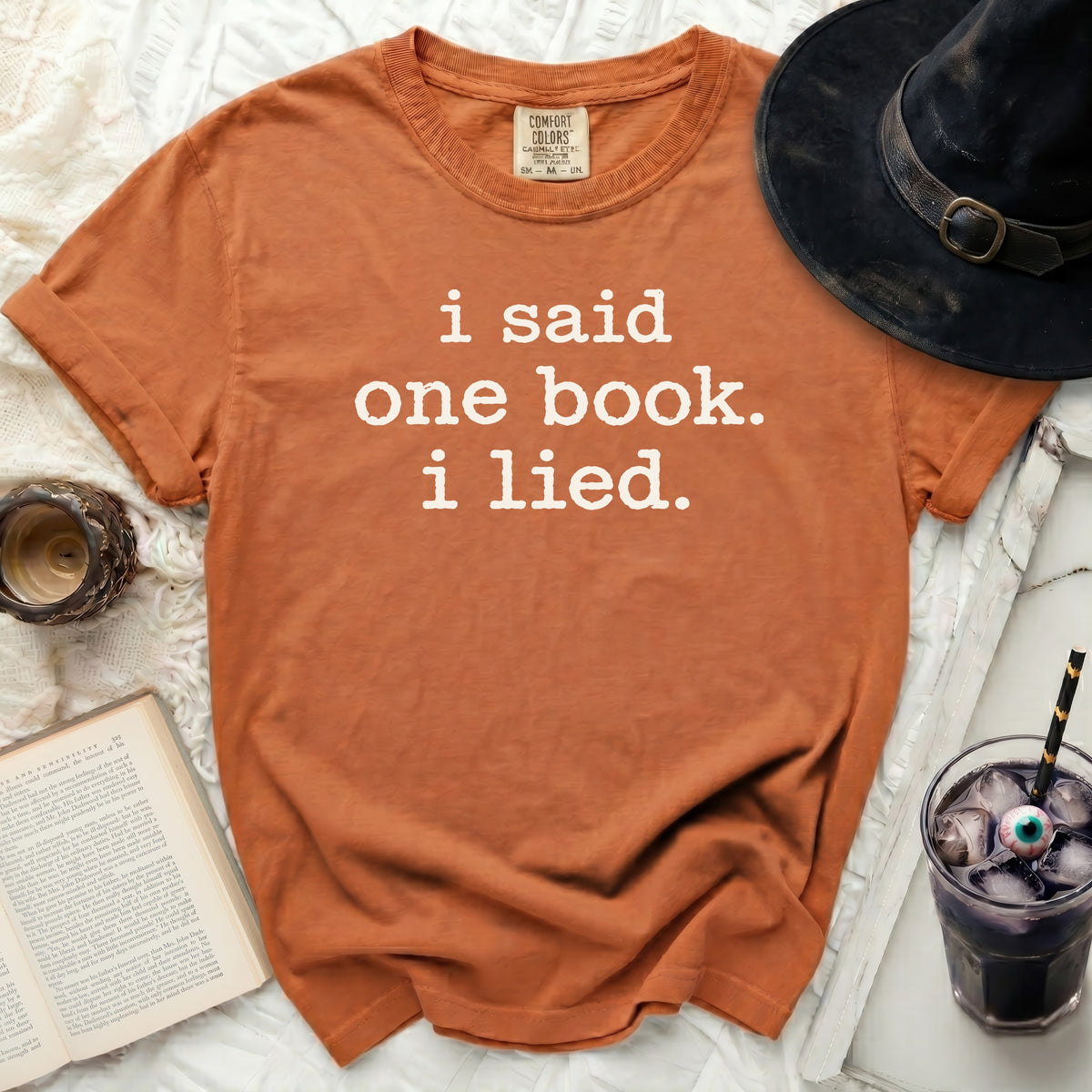 Orange t-shirt with white text that says "i said one book. i lied."