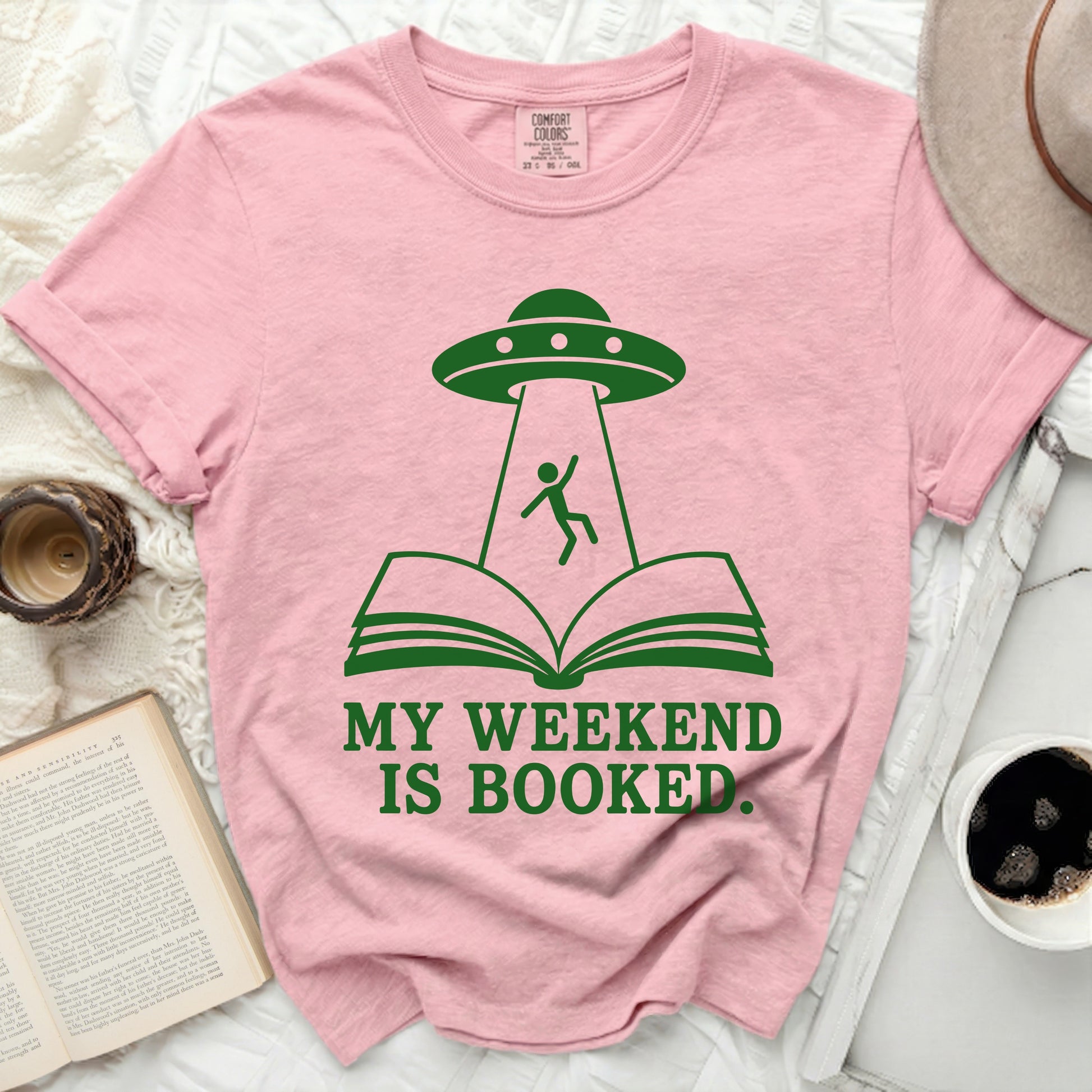 Pink t-shirt with UFO abducting person from open book.