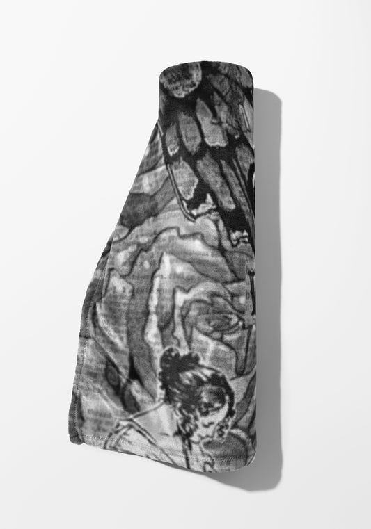Rolled blanket with black and white abstract pattern and draped edges.