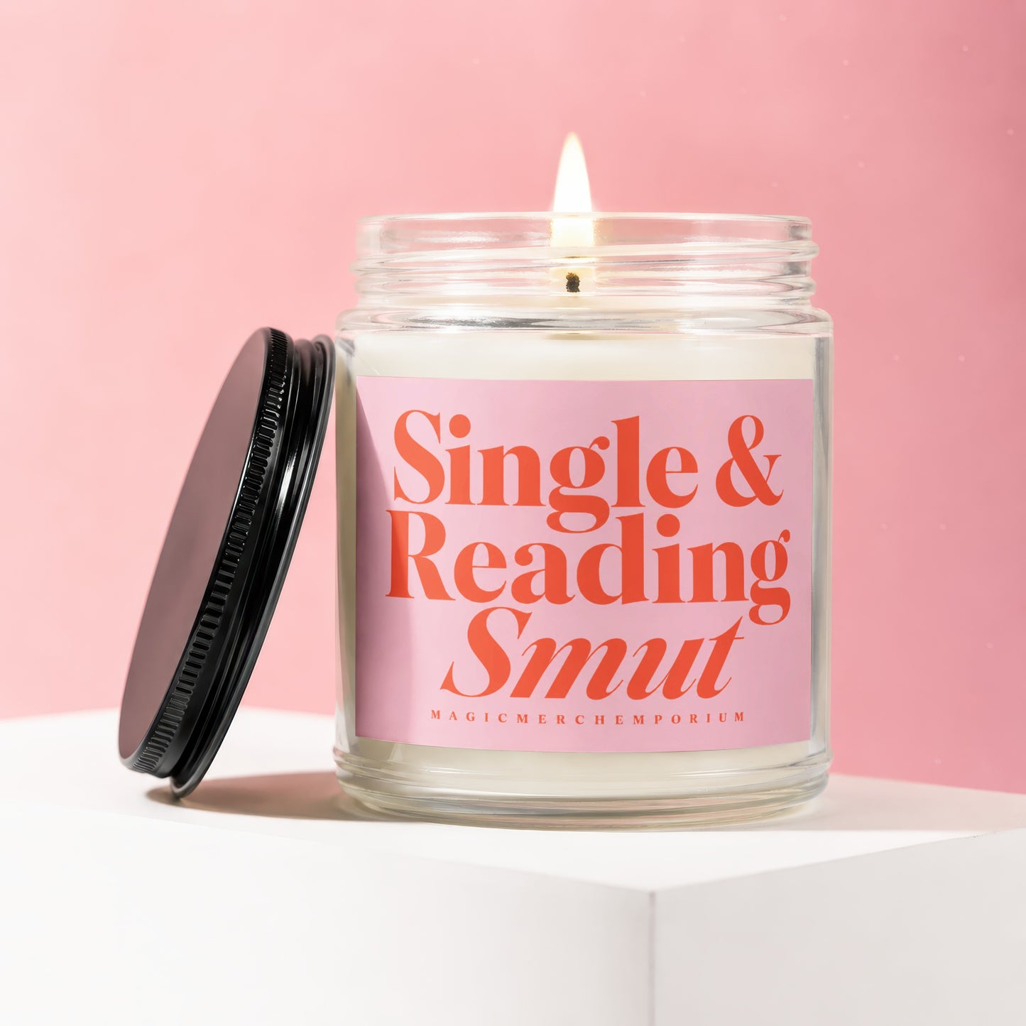 Glass candle with pink label reading "Single & Reading Smut" on pink background.