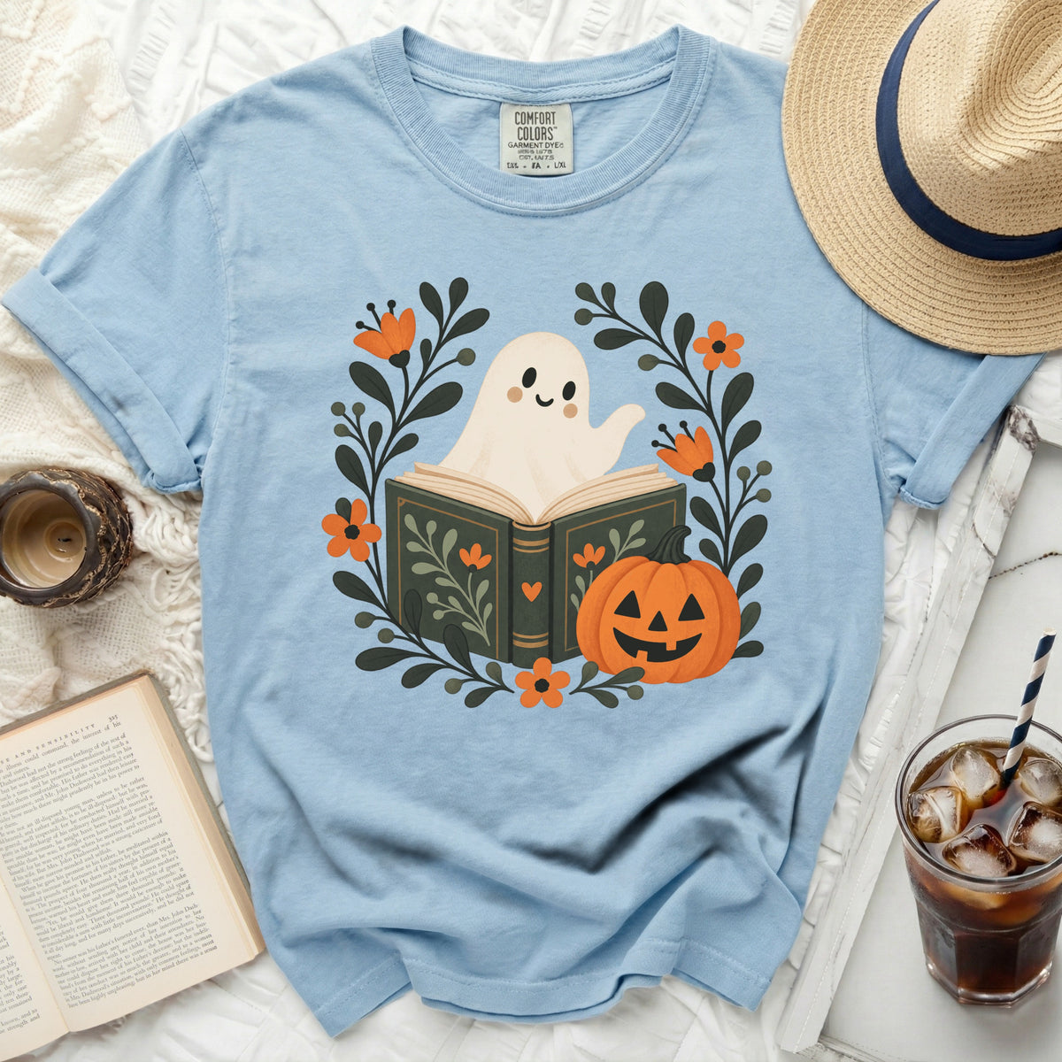 Light blue t-shirt with a ghost reading a book, surrounded by Halloween floral design.