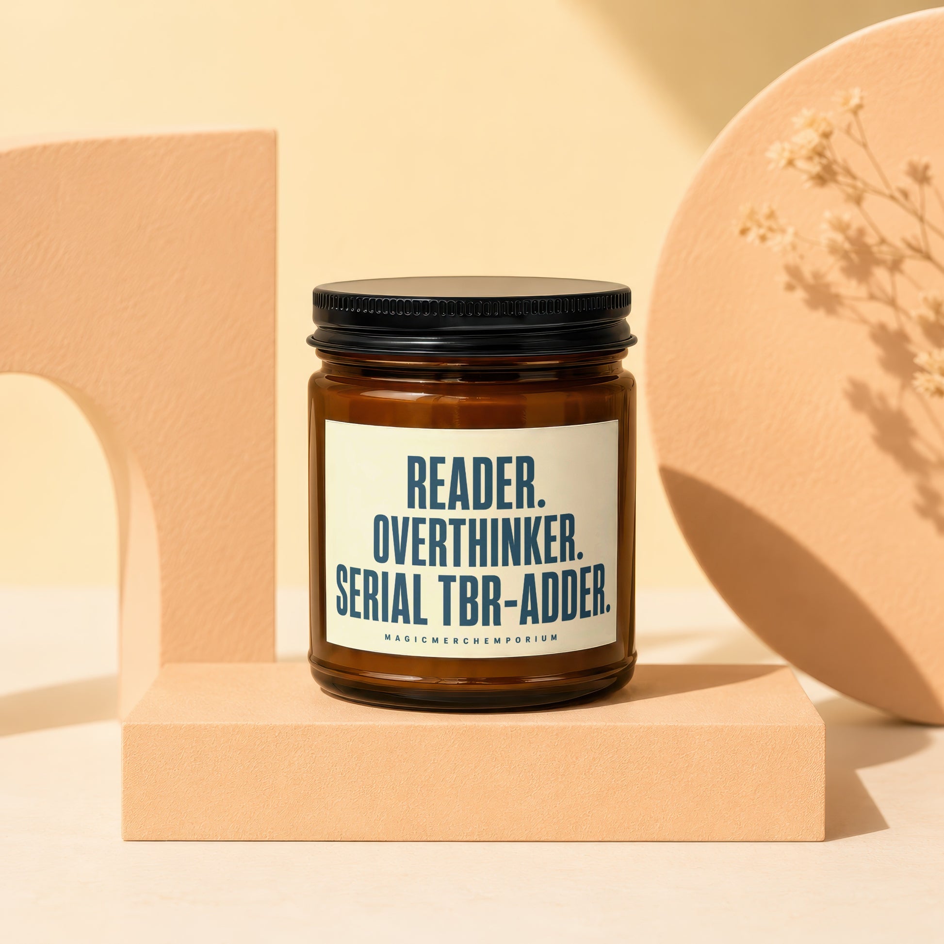 Amber jar candle with black lid featuring text: READER. OVERTHINKER. SERIAL TBR-ADDER.