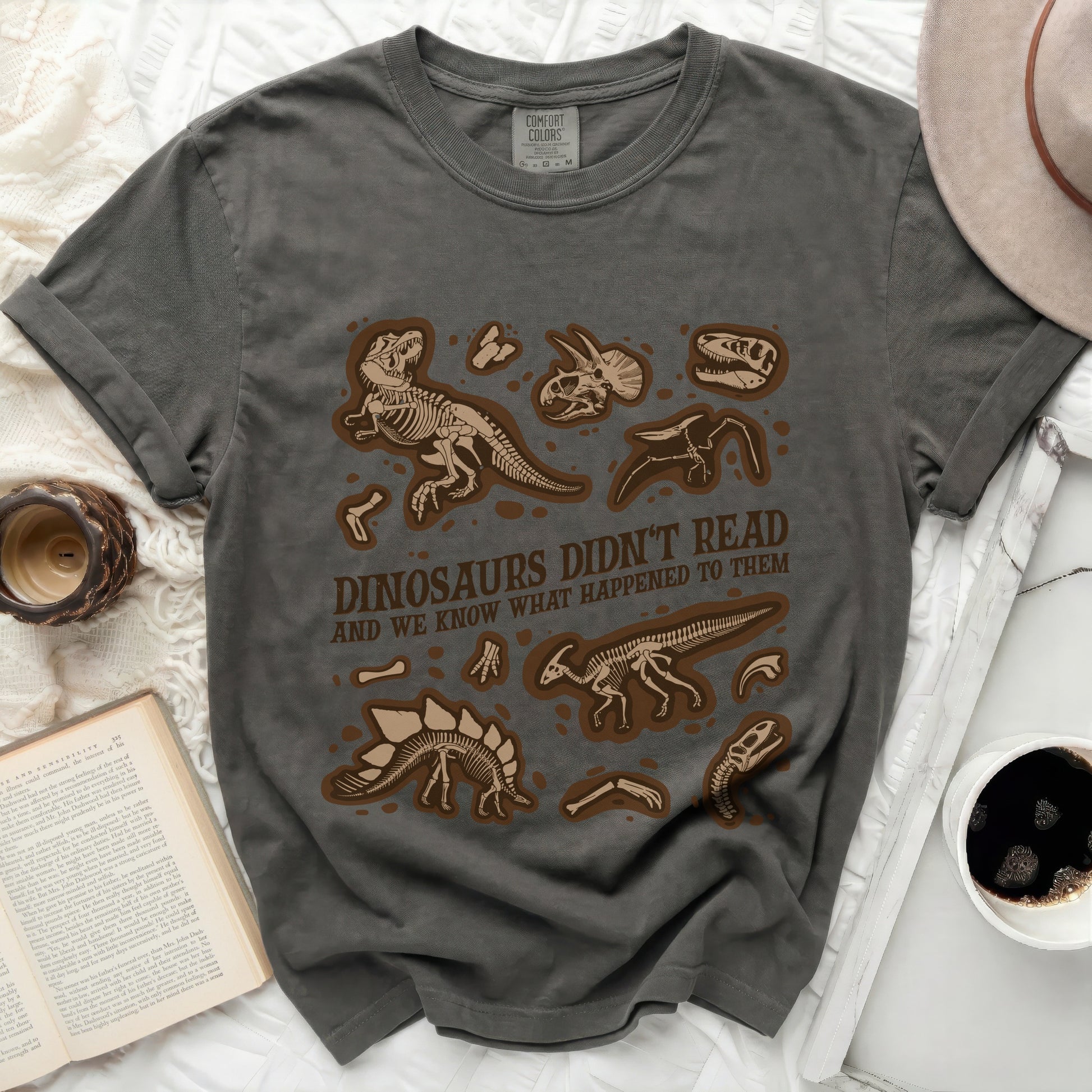 Grey t-shirt with dinosaur skeletons and text "DINOSAURS DIDN'T READ AND WE KNOW WHAT HAPPENED TO THEM".
