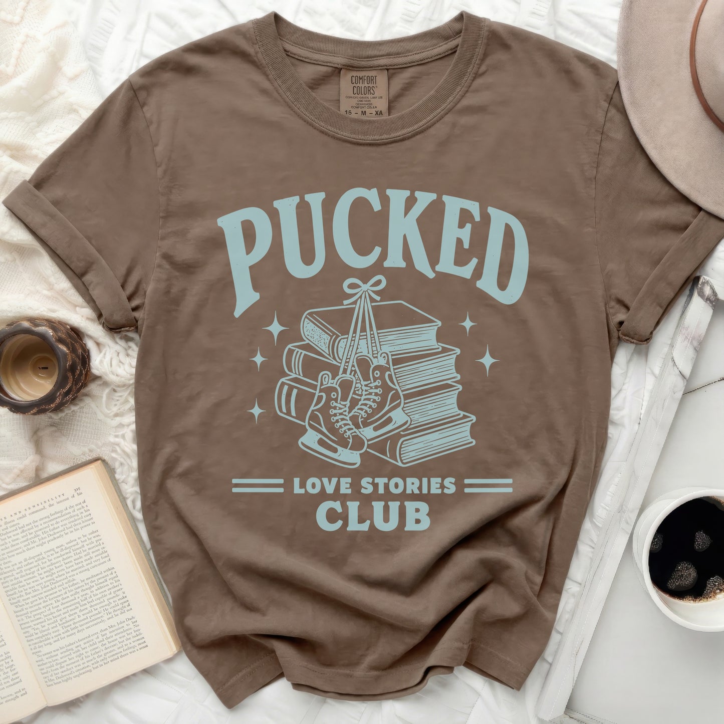 Brown t-shirt with "Pucked Love Stories Club" graphic featuring skates and books.
