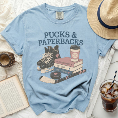 Light blue t-shirt with "Pucks & Paperbacks" and book and hockey graphics.