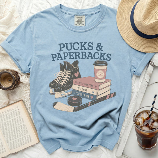 Light blue t-shirt with "Pucks & Paperbacks" and book and hockey graphics.