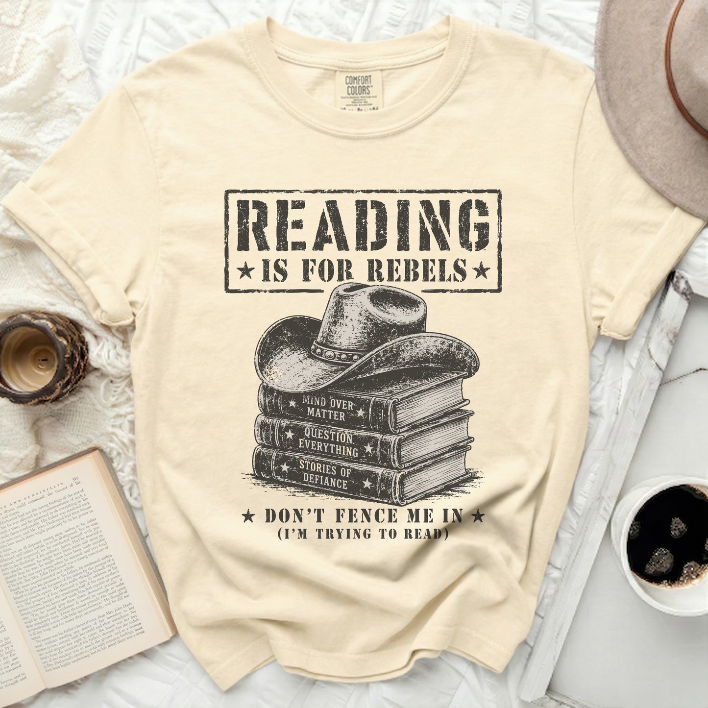 Cream t-shirt with "Reading is for Rebels" and stack of books with cowboy hat.