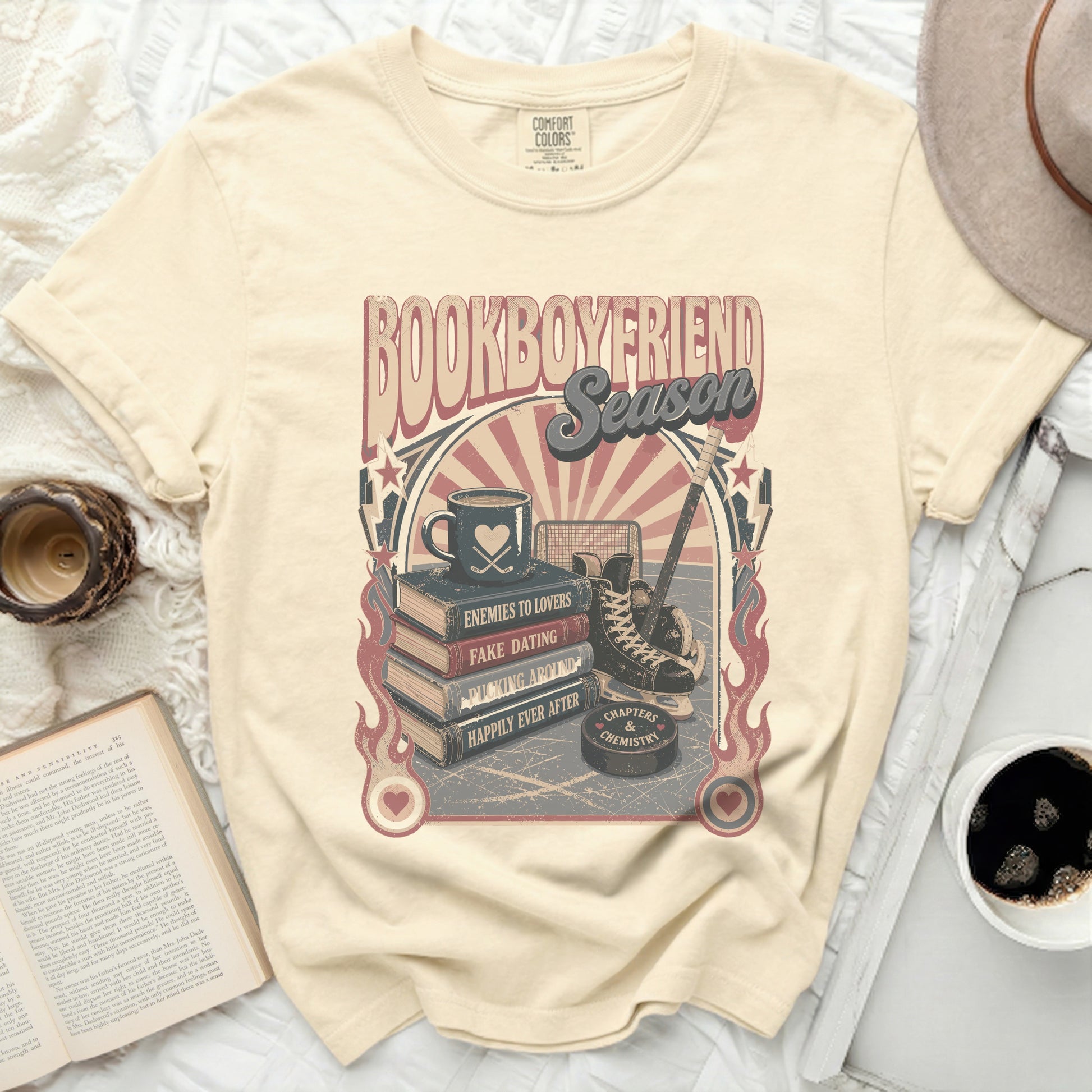 "Book Boyfriend Season" graphic tee with books, ice skates, hockey pucks, and flames.