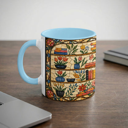 Mug with light blue handle and interior, featuring a stained glass print of books and flowers.
