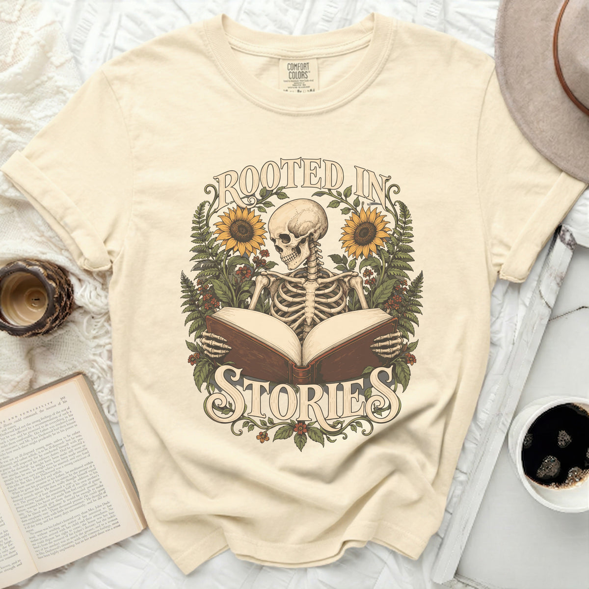 Skeleton reading an open book surrounded by sunflowers and greenery, text "Rooted in Stories".
