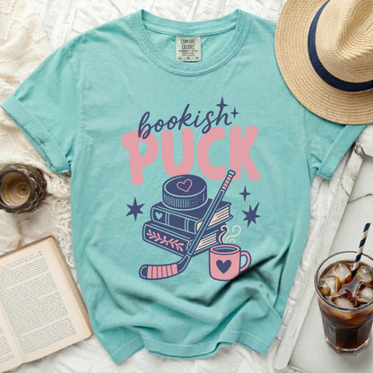 Aqua t-shirt with "bookish+ PUCK" text, hockey stick, books, and stars.