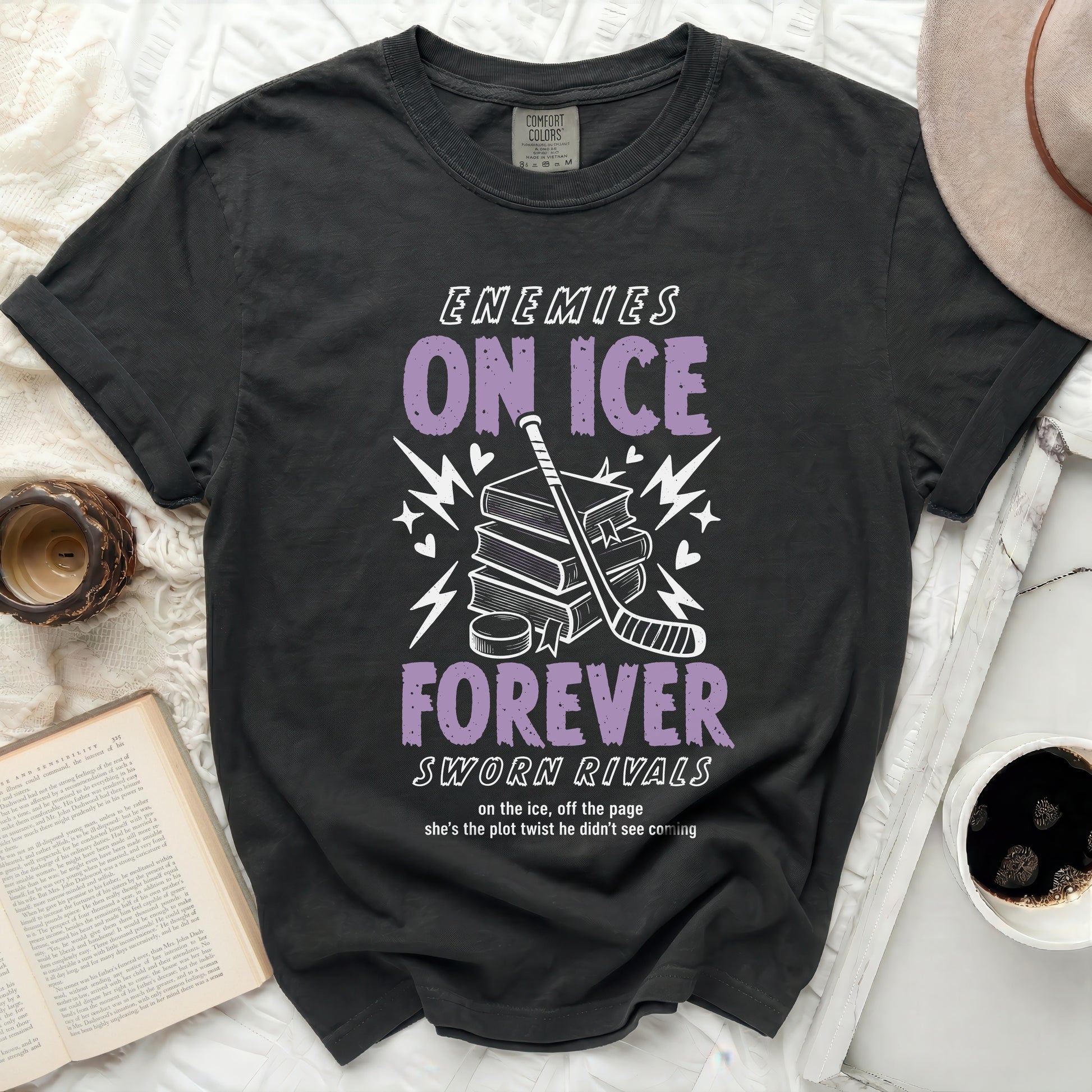 Dark t-shirt with "ENEMIES ON ICE SWORN RIVALS" text, hockey gear, and books.