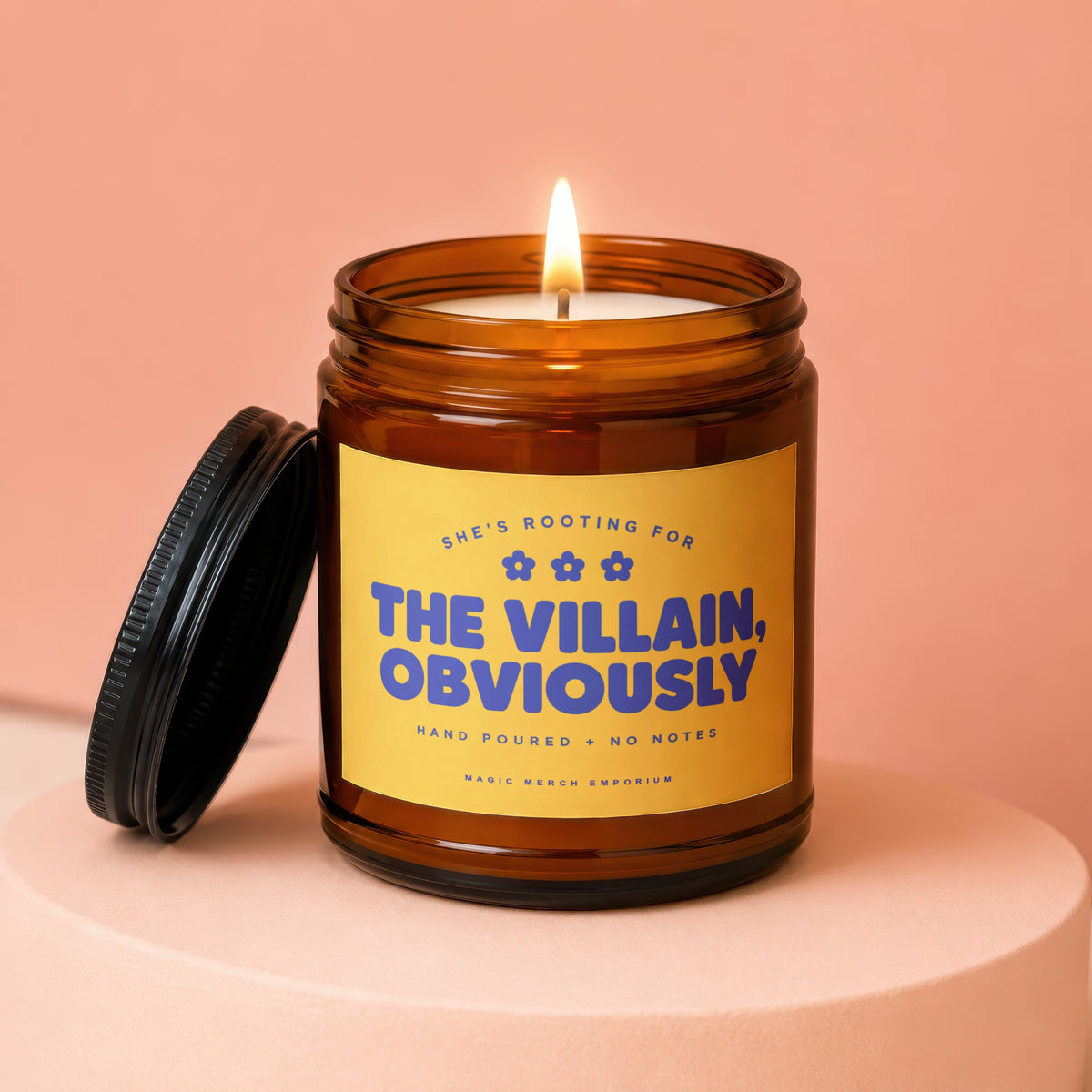 Amber jar candle with lit wick, "The Villain, Obviously" text.