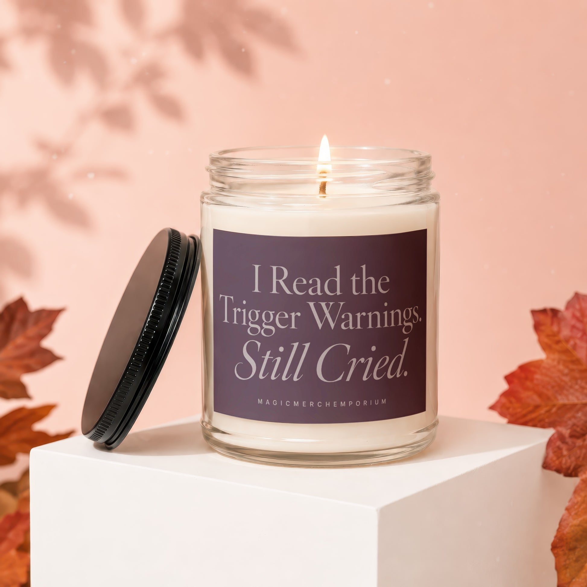 Glass jar candle with lit wick, purple label reads "I Read the Trigger Warnings, Still Cried."