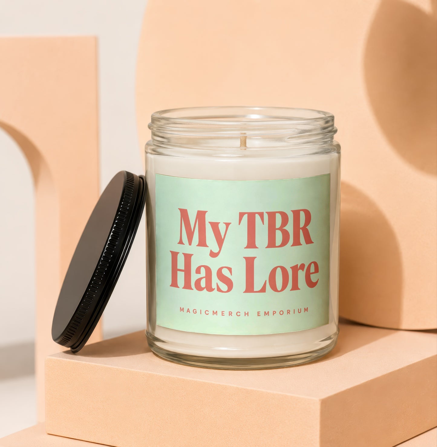 Glass jar candle with light green label reading "My TBR Has Lore" and "MAGICMERCH EMPORIUM".