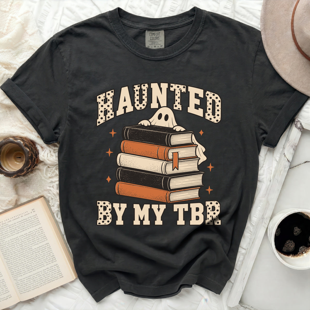 T-shirt with a ghost peeking over a stack of books and text "Haunted by my TBR."
