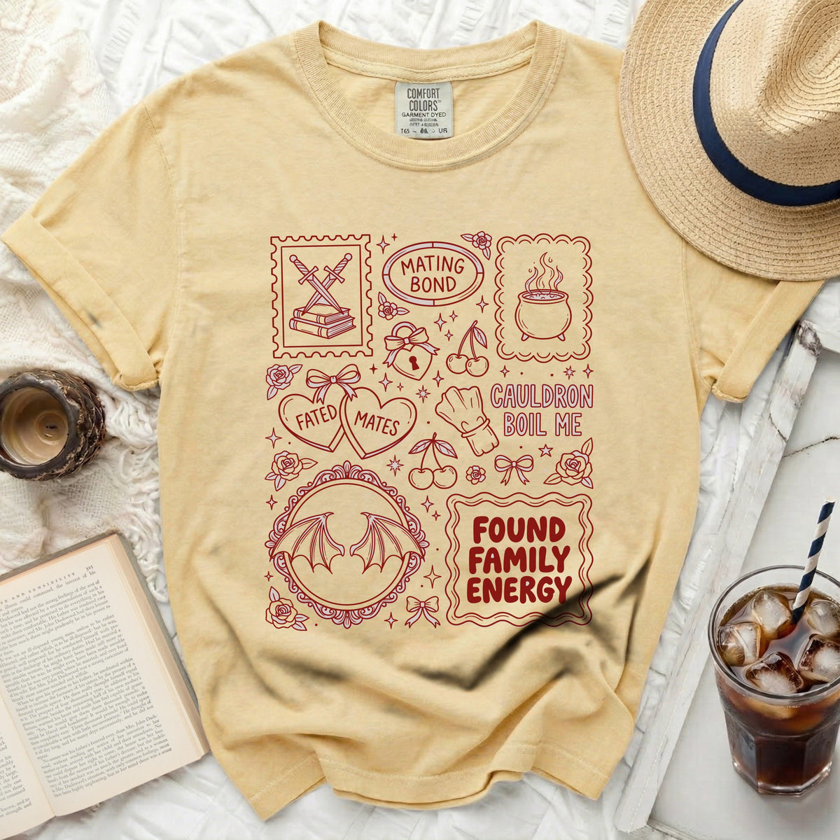 Yellow t-shirt with red graphic of stamps: "Mating Bond", "Cauldron Boil Me", "Found Family Energy", and others.