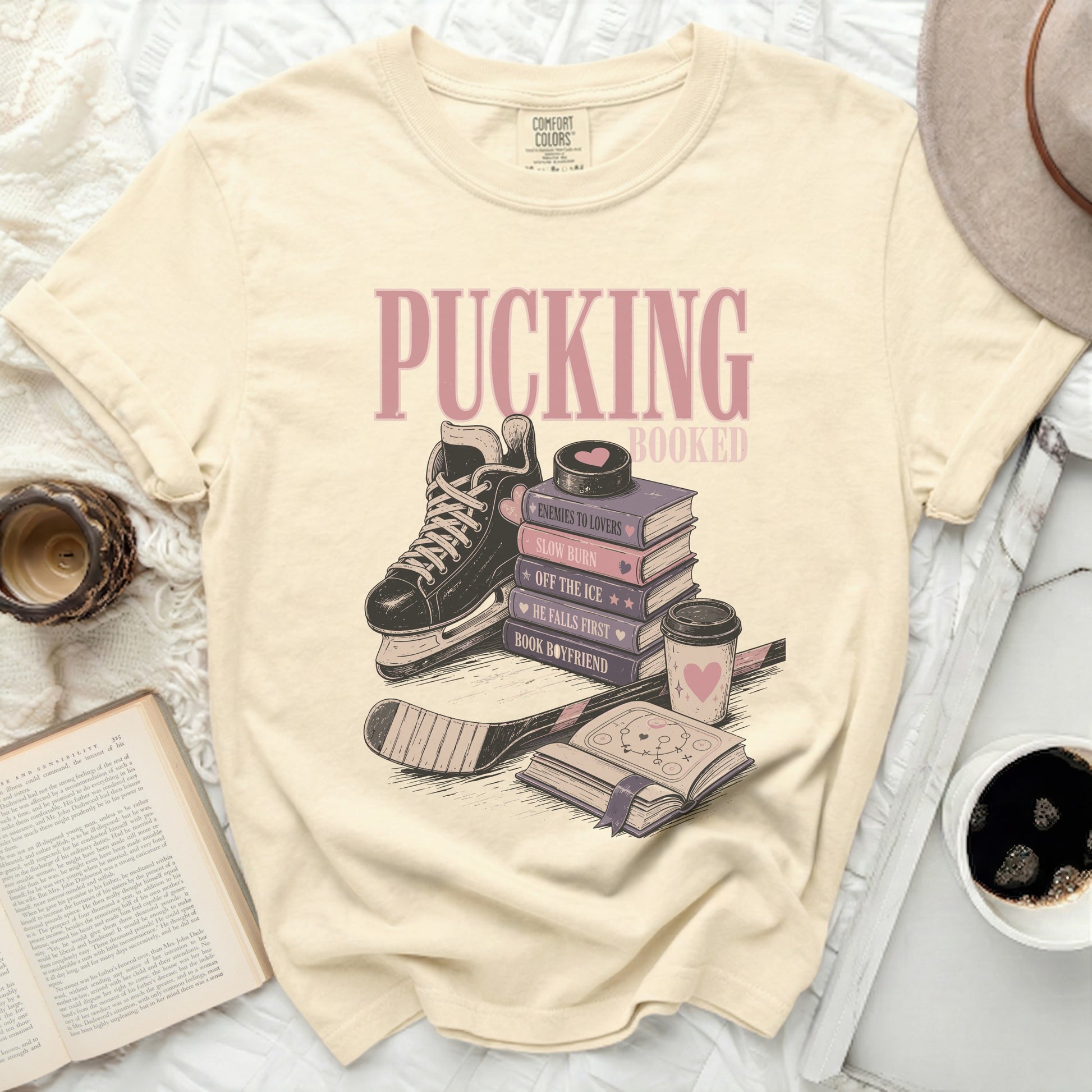 Cream t-shirt with "Pucking Booked" and stacked books with ice skate.