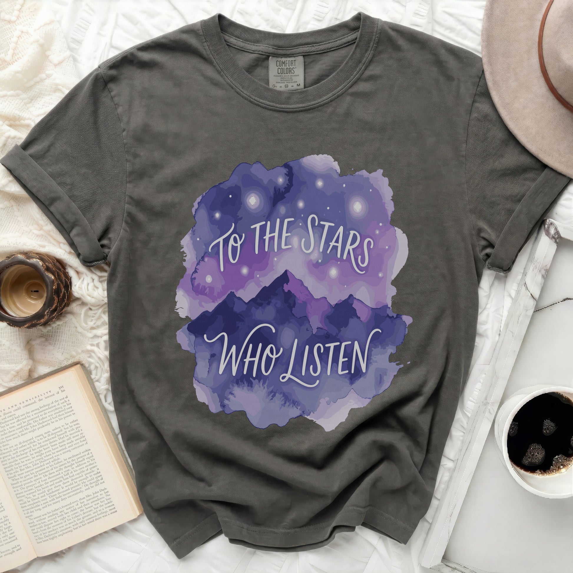 Dark gray t-shirt with "To the Stars Who Listen" text and starry mountain art.