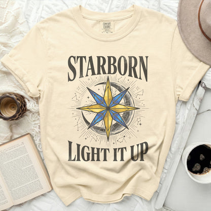 Cream t-shirt with "STARBORN LIGHT IT UP" text and celestial graphic.