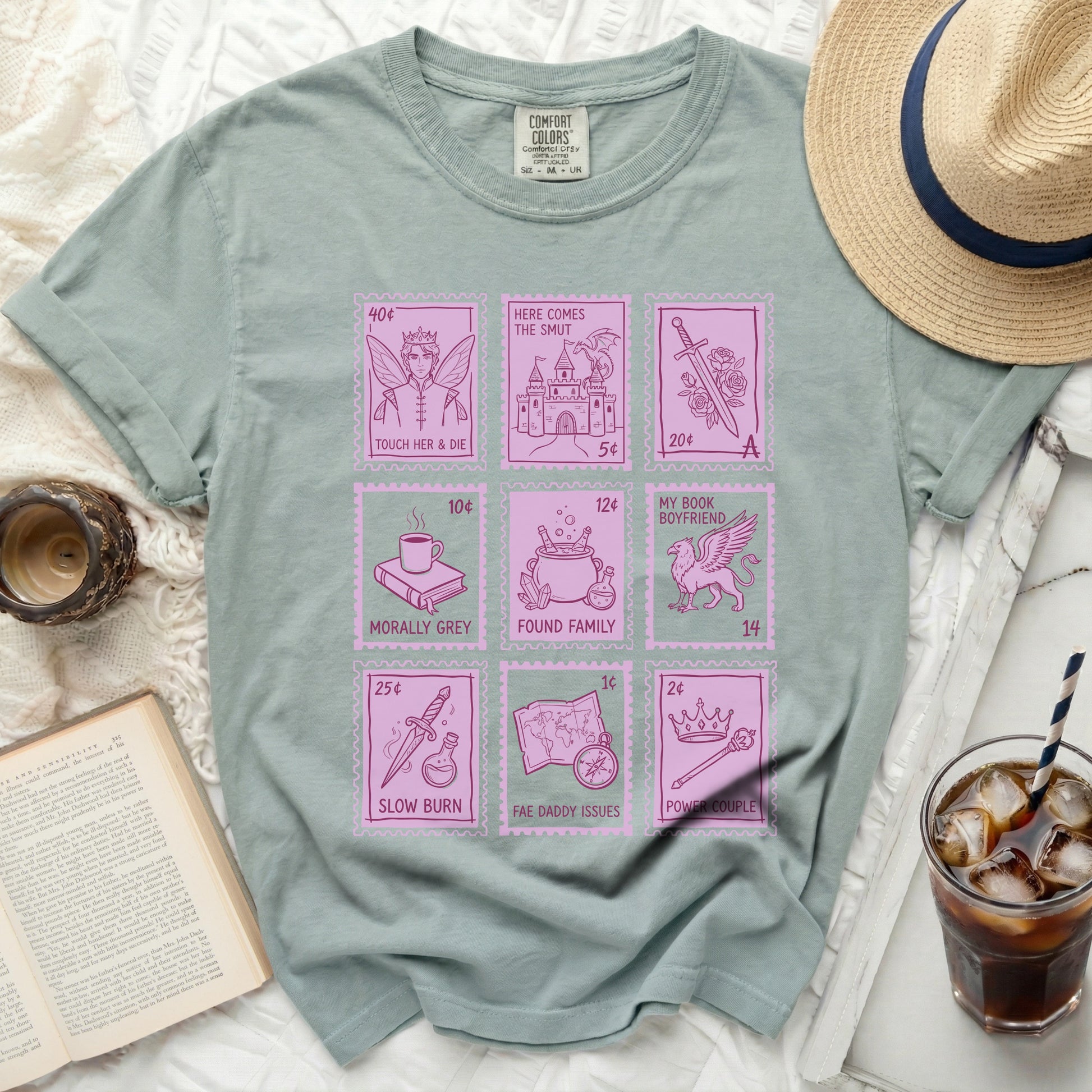 Green t-shirt with pink stamps: "Touch Her & Die," "My Book Boyfriend," "Morally Grey," "Found Family," "Slow Burn," "Fae Daddy Issues," "Power Couple."