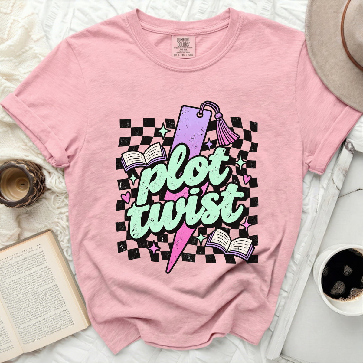 Pink t-shirt with "plot twist" graphic, books, and checkered pattern.