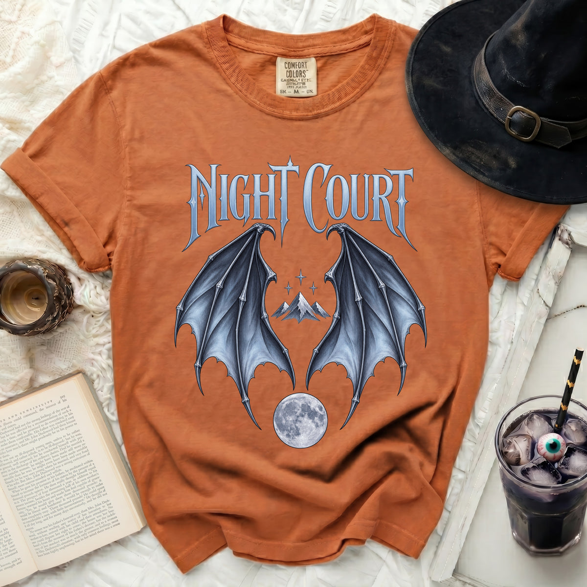 Orange t-shirt with "Night Court" text, bat wings, mountains, and moon graphic.