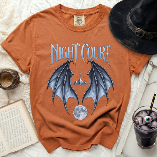 Orange t-shirt with "Night Court" text, bat wings, mountains, and moon graphic.