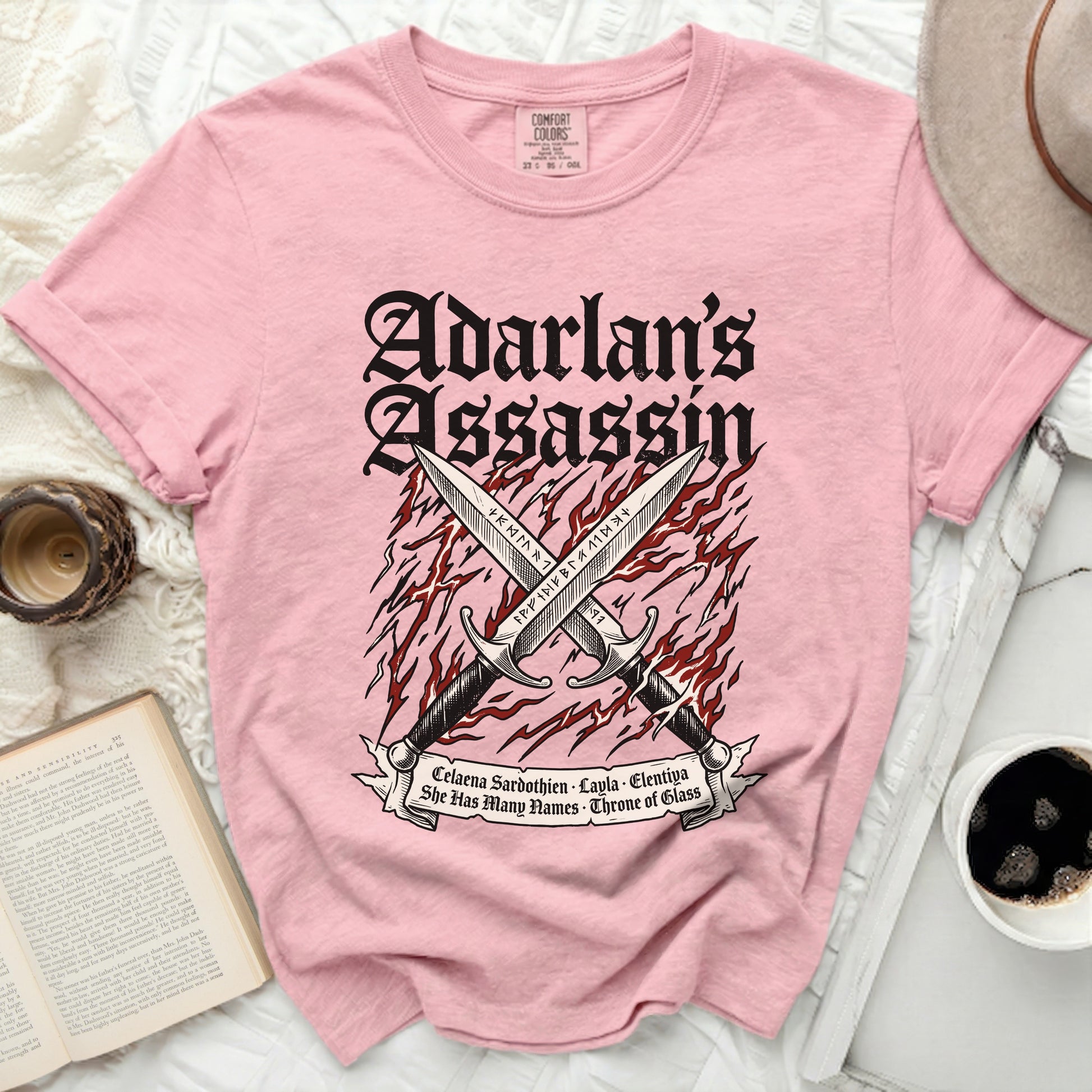 Pink t-shirt with crossed swords and "Adarlan's Assassin" text.