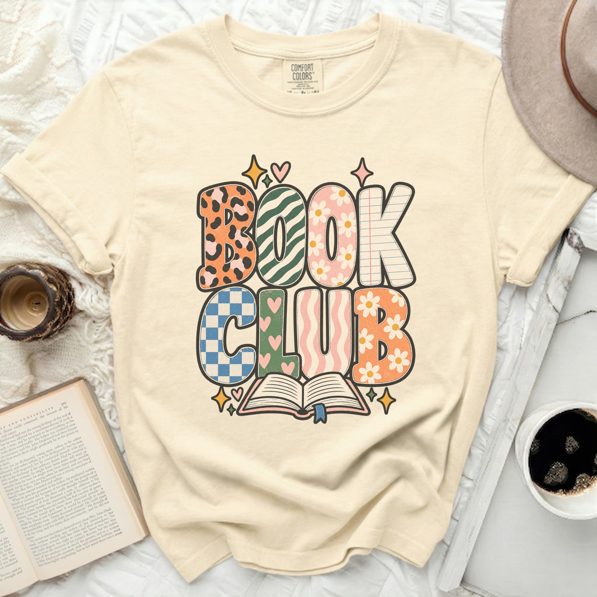 Cream t-shirt with "BOOK CLUB" graphic featuring colorful, patterned letters.